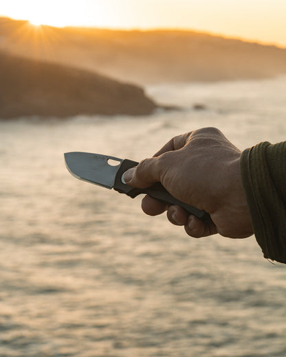 Olive Knives LENTA EDC folding knife, Elmax steel — lifestyle, held at the coast during sunset